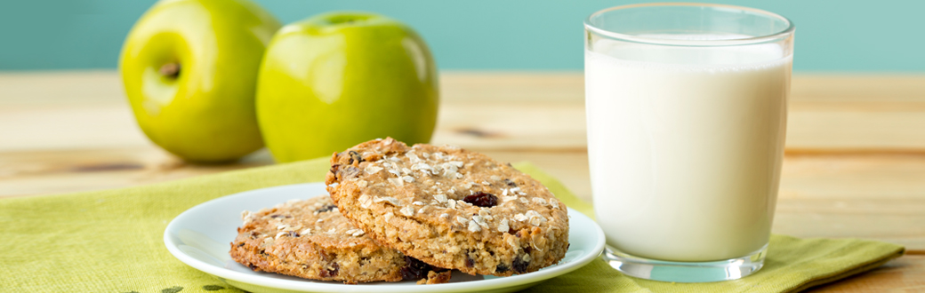 Apple breakfast cookies on a plate next to a glass of milk.