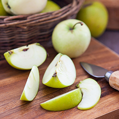 Green apples slices on a wood cutting board.